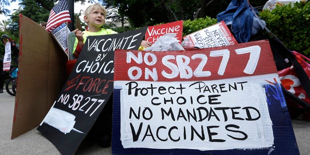 April 8, 2015: Zach Bingham, 6, sits among protest signs at against a measure requiring California schoolchildren to get vaccinated at a Capitol rally in Sacramento. (AP Photo/Rich Pedroncelli)
