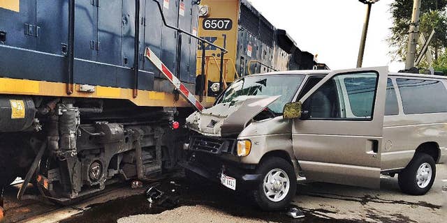 In this Tuesday, July 28, 2015 photo, a van rests against a train engine after a collision in Middletown, Ohio. An adult was killed and 10 others were injured when the van, transporting students to evening vacation Bible school, crashed into the side of the train. The Ohio State Highway Patrol said the gates were down and the warning lights activated at the crossing when the van approached. (Todd Jackson/WHIO-TV) MANDATORY CREDIT.