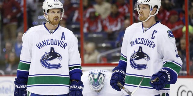 Dec 2, 2014; Washington, DC, USA; Vancouver Canucks left wing Daniel Sedin (22) and Canucks center Henrik Sedin (33) stand on the ice against the Washington Capitals in the first period at Verizon Center. Mandatory Credit: Geoff Burke-USA TODAY Sports