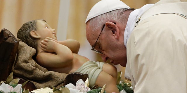 Pope Francis kisses during statue of baby Jesus a Mass in St. Peter's Basilica, at the Vatican, to mark Epiphany, Wednesday, Jan. 6, 2016. The Epiphany day is a joyous day for Catholics in which they recall the journey of the Three Kings, or Magi, to pay homage to Baby Jesus (AP Photo/Gregorio Borgia)