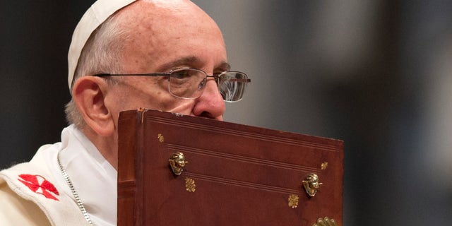 Pope Francis kisses the Holy Book as he celebrates a mass in St. Peter's Basilica on Jan. 1, 2014.