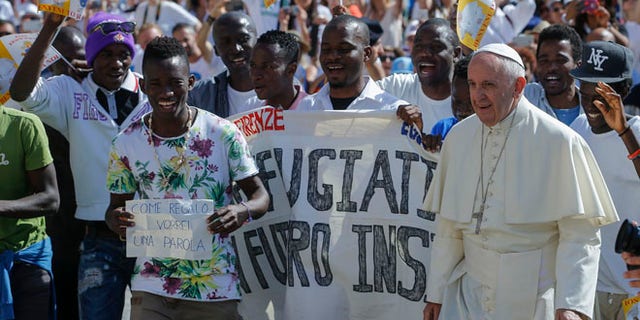 FILE- In this file photo dated Wednesday, June 22, 2016, Pope Francis walks with a group of refugees he invited to join him on the steps of St. Peter's Basilica during his weekly general audience in St. Peter's Square at the Vatican. Pope Francis begins a five-day visit to Poland on upcoming Wednesday July 27, 2016, and hopes to inspire aid to homeless strangers and acts of mercy for refugees during his visit, although Poland has closed its borders to refugees. (AP Photo/Fabio Frustaci, FILE)