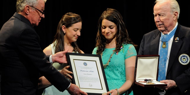 Sisters Jillian Soto, center left, and Carlee Soto, center right, accept the citizen honor of the Congressional Medal of Honor from Medal of Honor Recipient presenters, Thomas Kelley, left, and Bruce Crandall, right, on behalf of their late sister Victoria Soto in Newtown, Conn., Monday, May 6, 2013. The Congressional Medal of Honor Society says Rachel D'Avino, Dawn Hochsprung, Anne Marie Murphy, Lauren Rousseau, Mary Sherlach and Victoria Soto exemplified courage, sacrifice and selflessness in trying to protect students from the gunman at Sandy Hook Elementary School. (AP Photo/Jessica Hill)