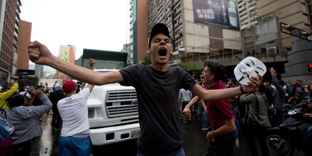 A demonstrator shouts slogans against Venezuela's President Nicolas Maduro as protesters block a road in Caracas, Venezuela, Thursday, Feb. 12, 2015. Venezuelans staged dueling marches to mark the anniversary of last year's bloody protest movement that resulted in more than 40 people being killed, including both government supporters and opponents. Dozens of protesters remain jailed, while the social issues they railed against last year- a faltering economy, widespread shortages and pervasive violent crime - have only gotten worse. (AP Photo/Fernando Llano)