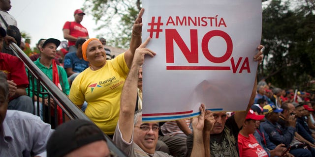 Supporters of President Nicolas Maduro hold a sign that reads in Spanish "Amnesty will not go" during a march, at Miraflores Presidential Palace in Caracas, Venezuela, Thursday, April 7, 2016. Groups allied to Venezuela's socialist administration marched to protest an amnesty law passed by the opposition controlled congress calling for release of those it deems to be political detainees. (AP Photo/Ariana Cubillos)