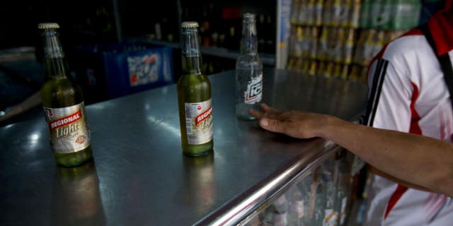 In this Tuesday, July 28, 2015 photo, a customer returns an empty Polar beer bottle and buys two others by another maker after Polar beers sold out at the store in Caracas, Venezuela. Starting Monday, at least two of Polar's six beer plants are closing temporarily for lack of ingredients, affecting 25% of beer production in a country with one of the highest beer consumption rates in the world. Venezuela's President Nicolas Maduro blames food and goods shortages on an economic war waged by opposition aligned companies, while economists point to the country's price controls since 2003. (AP Photo/Fernando Llano)