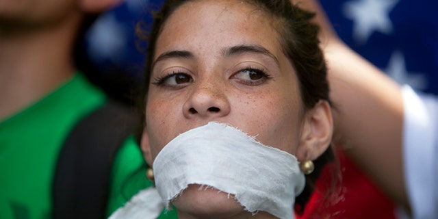 A demonstrator covers her mouth with a rag to prostest government censorship, during a march to Venezuelan Telecommunications Regulator Office or CONATEL in Caracas, Venezuela, Monday, Feb17, 2014. Students, whoâve spent the past week on the streets alternating between peaceful protests by day and battles with police at night, marched on Monday to Venezuelaâs telecom regulator to demand it lift all restrictions on the mediaâs coverage of the unfolding political crisis. (AP Photo/Alejandro Cegarra)