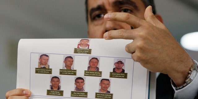 Venezuela's Interior and Justice Minister, Army Gen. Miguel Rodriguez Torres displays photos of men suspected by the government of planning to assassinate Venezuela's President Nicolas Maduro and National Assembly President Disodado Cabello, at a news conference at his office in Caracas, Venezuela, Monday Aug. 26, 2013.  Rodriguez Torres said that the group consists of 10 Colombian men, and that two have been arrested. (AP Photo/Fernando Llano)