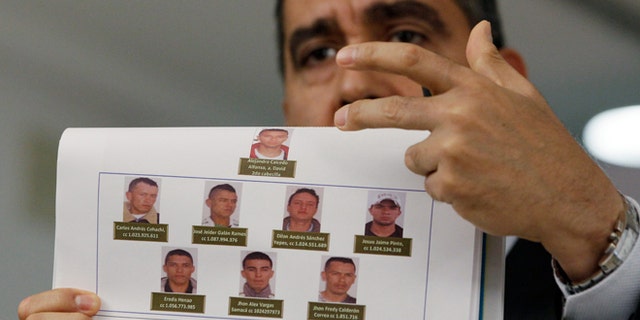 Venezuela's Interior and Justice Minister, Army Gen. Miguel Rodriguez Torres displays photos of men suspected by the government of planning to assassinate Venezuela's President Nicolas Maduro and National Assembly President Disodado Cabello, at a news conference at his office in Caracas, Venezuela, Monday Aug. 26, 2013. Rodriguez Torres said that the group consists of 10 Colombian men, and that two have been arrested. (AP Photo/Fernando Llano)