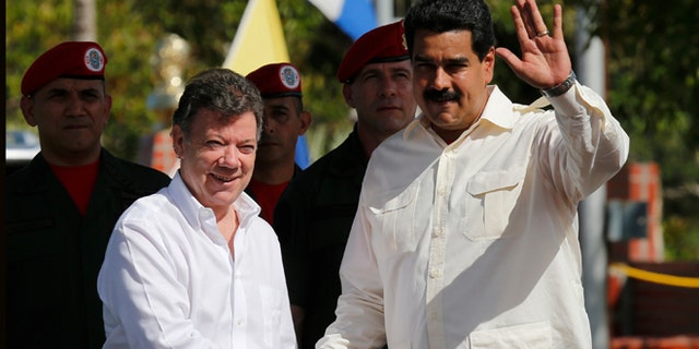 Venezuela's President Nicolas Maduro, right, waves as he shakes hands with Colombia's President Juan Manuel Santos prior a meeting in Puerto Ayacucho, Venezuela, Monday, July 22, 2013. (AP Photo/Fernando Llano)