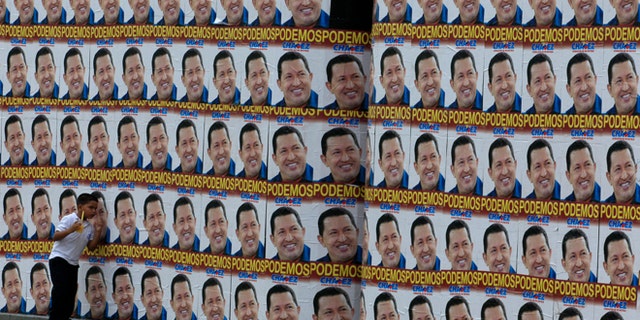 A boy walks beside a a wall covered with campaign posters of Venezuela's President Hugo Chavez in Caracas, Venezuela, Tuesday, Sept. 25, 2012. Chavez held a 10-point lead over rival Henrique Capriles in a polling company's final survey ahead of the Oct. 7 election, but the report released Tuesday showed Capriles narrowing the gap. (AP Photo/Fernando Llano)