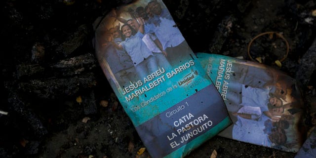 Nov. 24, 2015: Singed flyers promoting opposition congressional candidate Marialbert Barrios is seen on top of a trash pile at the Catia neighborhood, in Caracas, Venezuela. Remains of burned flyers and posters of opposition congressional candidates show traces of a battle that was fought in a busy street in the populous neighborhood Tuesday, after a group of alleged government supporters, some armed and on motorbikes, arrived and violently attacked supporters of the opposition as they hung election posters and flyers promoting their candidates. (AP Photo/Ariana Cubillos)