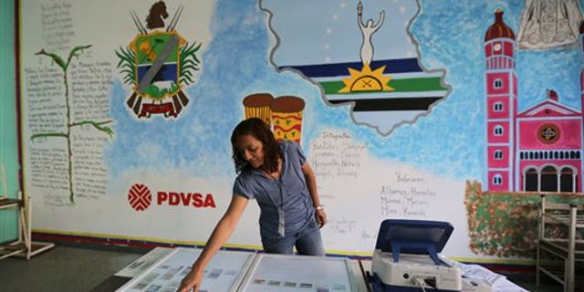 A member of the Venezuelan National Electoral Council tests a voting machine at a polling station in Caracas, Venezuela, Friday, Dec. 6, 2013. Venezuelans will vote in nationwide municipal elections Sunday. (AP Photo/Fernando Llano)