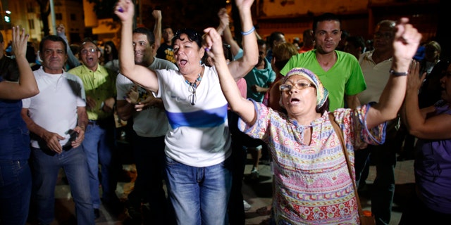 Dec. 6, 2015: Opposition supporters celebrates the closing of a polling station during congressional elections in Caracas, Venezuela. Some members of the opposition are angry after elections officials ordered polling centers to stay open for an extra hour, even if no one was standing in line to vote. Government opponents mobbed some voting stations demanding that the National Guard stick to the original schedule of closing at 6 p.m. (AP Photo/Ariana Cubillos)