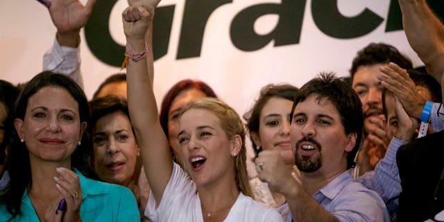 Lilian Tintori wife of jailed Venezuelan opposition leader Leopoldo Lopez, center, Freddy Guevara, of the Voluntad Popular party, right, and former opposition congresswoman Maria Corina Machado, left, celebrate in Caracas, Venezuela, early Monday, Dec. 7, 2015. Venezuela's opposition won control of the National Assembly by a landslide on Sunday, delivering a major setback to the ruling party and altering the balance of power after 17 years of socialist rule.(AP Photo/ Alejandro Cegarra)