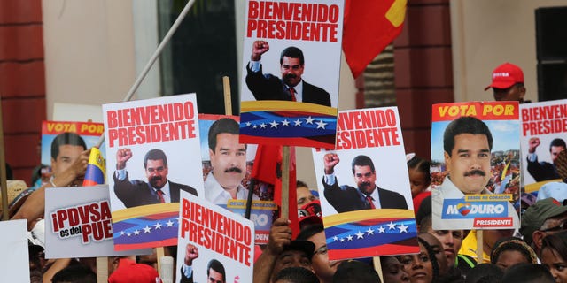 Supporters hold placards with images of Venezuela's President Nicolas Maduro and a message that reads in Spanish; "Welcome president,"at the Miraflores Palace in Caracas, Venezuela, Saturday, Jan. 17, 2015, during a ceremony welcoming the leader back home. Maduro has been away visiting seven nations to seek loans and make a plea for lower oil production. The price of oil has crashed in recent months, driving Venezuelaâs oil-based economy to the brink. (AP Photo/Ariana Cubillos)
