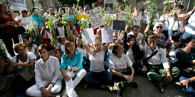 June 12, 2015: Flanked by Venezuela's former opposition lawmaker Maria Corina Machado, left center, and Mitzy Capriles de Ledezma, wife of imprisoned Caracas Mayor Antonio Ledezma, right center, Lilian Tintori, wife of jailed opposition leader Leopoldo Lopez, holds up a letter signed by supporters, during a demonstration at the entrance of the building where the Brazilian embassy operates in Caracas. (AP Photo/Ariana Cubillos)