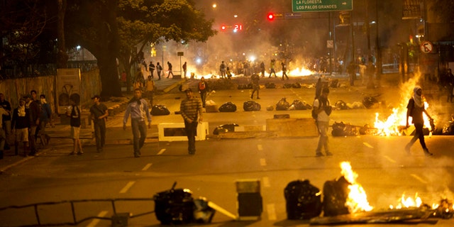 Objects placed by opposition protesters block a road in the Altamira neighborhood of Caracas, Venezuela, Thursday, Feb. 20, 2014. Violence is heating up in Venezuela as an opposition leader faces criminal charges for organizing a rally that set off escalating turmoil in the oil-rich, but economically struggling country. (AP Photo/Rodrigo Abd)