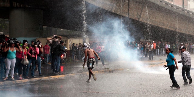 Mary 8, 2012: Relatives of inmates, protesting against measures taken by authorities to control a riot at the La Planta prison, run away from tear gas canisters fired by National Guard soldiers during clashes outside the prison in Caracas, Venezuela.