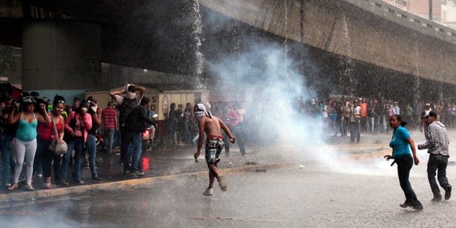 Mary 8, 2012: Relatives of inmates, protesting against measures taken by authorities to control a riot at the La Planta prison, run away from tear gas canisters fired by National Guard soldiers during clashes outside the prison in Caracas, Venezuela.