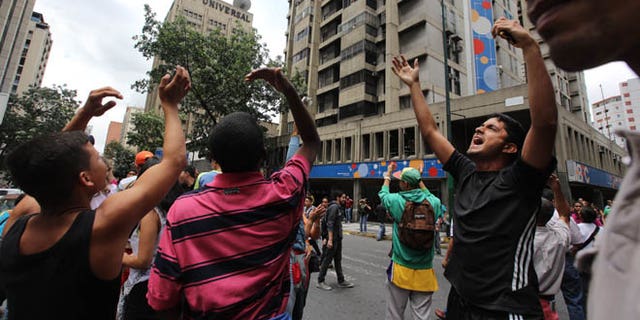 People call others in apartment and office buildings to join their protest demanding food, a few blocks from Miraflores presidential palace in Caracas, Venezuela, Thursday, June 2, 2016. Venezuela is seeing rising frustration with widespread food shortages and triple-digit inflation. (AP Photo/Fernando Llano)