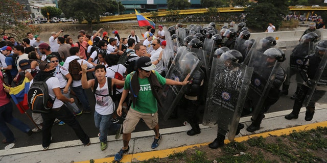Bolivarian National Police officers push demonstrators to prevent them from blocking the Francisco Fajardo highway in Caracas, Venezuela, Thursday, Feb. 27, 2014. Anti-government protesters rallied to demand an end to the government crackdown on protests and the release of those jailed in recent weeks. (AP Photo/Fernando Llano)