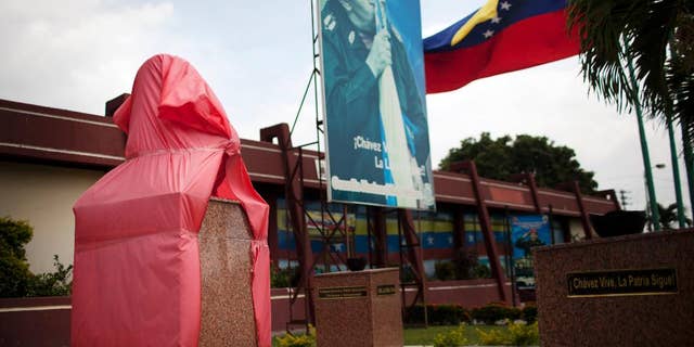 A new bust of former Venezuela's President Hugo Chavez is protected by a red fabric at a Bolivarian National Guard base in Valencia, Venezuela, Saturday, March 1, 2014. To mark Chavez’s passing, President Nicolas Maduro has decreed a 10 day-long commemoration - longer than the week-long period of official mourning that followed his death at the age of 58 on March 5, 2013. (AP Photo/Rodrigo Abd)