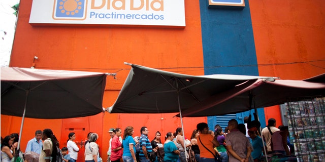 People line up outside the Dia a Dia supermarket after it was taken over by the government in the Propatria neighborhood of Caracas, Venezuela, Tuesday, Feb. 3, 2015. The government is temporarily taking over the Dia a Dia supermarket chain as part of a crackdown on private businesses it blames for worsening shortages and long lines. Popular items with government fixed prices that have been running short are coffee, cooking oil, precooked corn flour, sugar, milk, toilet paper, disposable diapers, detergent and fabric softener, among other items. (AP Photo/Ariana Cubillos)