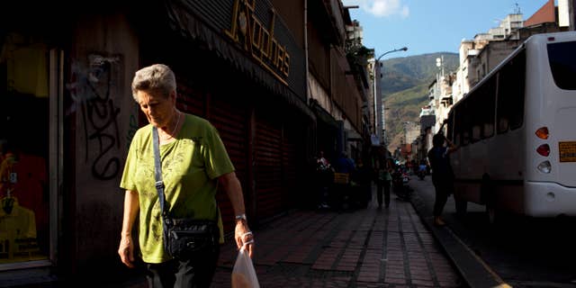 FILE - In this Feb. 20, 2014 file photo, a woman walks downtown after buying bread in Caracas, Venezuela. Venezuelans may soon have to scan their fingers to buy bread at the supermarket. President Nicolas Maduro announced late Wednesday, Aug. 20, 2014 a new, mandatory grocery fingerprinting system to combat food shortages. In the spring, Venezuela tried a similar system in government-run supermarkets on a voluntary basis. (AP Photo/Rodrigo Abd, File)