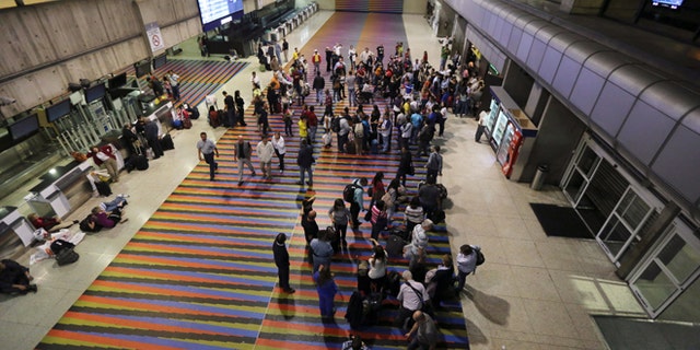 Passengers lineup in front of the Air France desk after their flight to Paris was called at Simon Bolivar Airport in Maiquetia near Caracas, Venezuela, Sunday, Dec. 15, 2013. Venezuelan bomb experts are inspecting a grounded Air France flight after being tipped off by French authorities that a terrorist group may be planning to detonate an explosive device in midair. Venezuelan Interior Minister Miguel Rodriguez Torres told state TV that a team of more than 60 technicians are performing an exhaustive search of the aircraft that will take several hours before the flight can be rescheduled.(AP Photo/Fernando Llano)