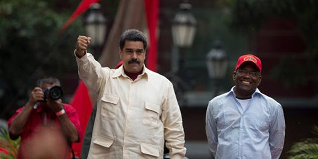 Venezuelas President Nicolas Maduro holds out his right fist while standing next to Vice President Aristobulo Isturiz during a ceremony marking the 206th anniversary of the call for independence from Spain, in Caracas, Venezuela, Tuesday, April 19, 2016. Opposition members are calling for Venezuelans to demonstrate across the country Tuesday to pressure Maduro to leave office. (AP Photo/Fernando Llano)