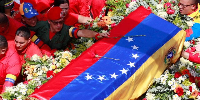 A member of the presidential guard, top, places a flower on the coffin containing the body of late President Hugo Chavez.