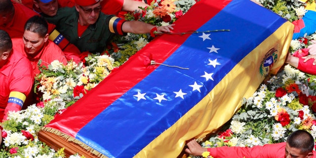 A member of the presidential guard, top, places a flower on the coffin containing the body of late President Hugo Chavez.