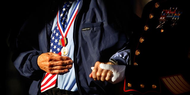 Marine Corps veteran Jim Brown, 83, (right) who served in Vietnam and Korea helps D-Day Veteran Howard Mills, 91, to the stage for special recognition during a Veteran's Day ceremony in Collierville, Tenn. Sunday, Nov. 10, 2013. (AP Photo/The Commercial Appeal, Jim Weber)