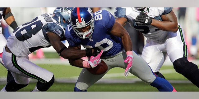 New York Giants wide receiver Victor Cruz (80) fumbles the ball as he is tackled by Seattle Seahawks defensive back Walter Thurmond (28) during the fourth quarter of an NFL football game Sunday, Oct. 9, 2011, in East Rutherford, N.J. The Seahawks won the game 36-25. (AP Photo/Julio Cortez)
