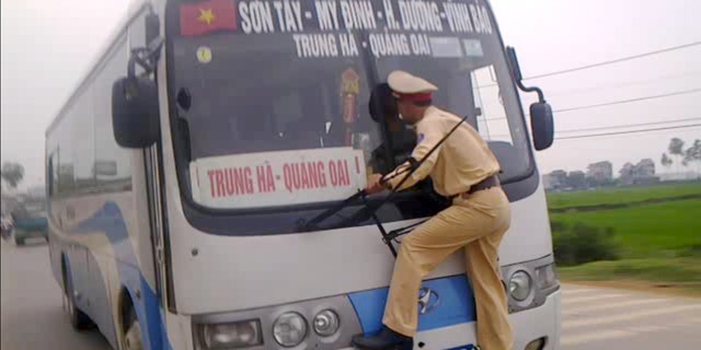 April 9, 2012: In this photo made from a video filmed and released by Hanoi Police, Vietnamese traffic police 2nd Lt. Nguyen Manh Phan clings on to the windshield wipers of a moving bus as he goes on a wild ride for nearly a 0.62 miles after the rogue driver tried to avoid a ticket in Ba Vi District outside Hanoi, Vietnam.
