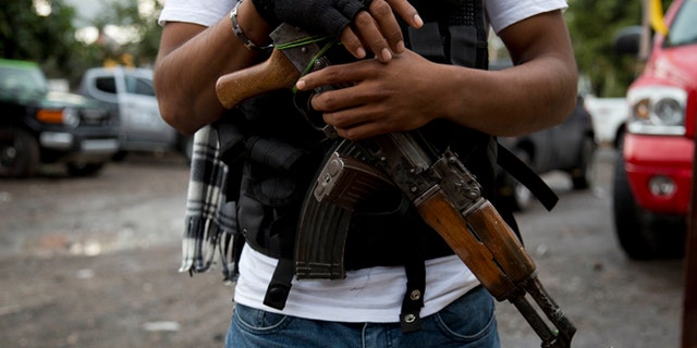 FILE - In this Jan. 16, 2014 file photo, an armed man belonging to the Self-Defense Council of Michoacan, (CAM), stands guard at a checkpoint set up by the self-defense group at the entrance to Antunez, Mexico. Mexico essentially legalized the countryâs growing âself-defenseâ groups Monday, Jan. 27, 2014, while also announcing that security forces had captured one of the four top leaders of the Knights Templar drug cartel, which the vigilante groups have been fighting for the last year. The government said it had reached an agreement with vigilante leaders to incorporate the armed civilian groups into old and largely forgotten quasi-military units called the Rural Defense Corps. (AP Photo/Eduardo Verdugo, File)