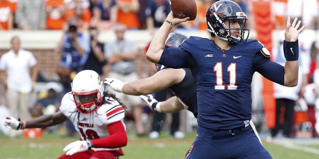 Sep 13, 2014; Charlottesville, VA, USA; Virginia Cavaliers quarterback Greyson Lambert (11) throws the ball as Louisville Cardinals cornerback Terell Floyd (19) chases in the fourth quarter at Scott Stadium. The Cavaliers won 23-21. Mandatory Credit: Geoff Burke-USA TODAY Sports