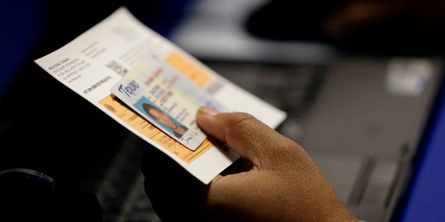 FILE - In this Feb. 26, 2014, file photo, an election official checks a voter's photo identification at an early voting polling site in Austin, Texas. A federal appeals court ruled Wednesday, July 20, 2016, that Texas' strict voter ID law discriminates against minorities and the poor and must quickly be scrubbed of those effects before the November 2016 election. Voters will still need to show identification at the polls under the decision by the New Orleans-based 5th U.S. Circuit Court of Appeals, according to attorneys who challenged the law, but a lower court will now also have to devise a way for Texas to accommodate those who cannot. (AP Photo/Eric Gay, File)