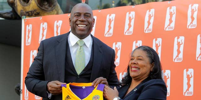 FILE - In this Feb. 5, 2014, file photo, former Los Angeles Laker Magic Johnson is joined by WNBA President Laurel Richie as they pose for photographers after a news conference in front of Staples Center in Los Angeles. Johnson is part of a group buying the Los Angeles Sparks of the WNBA. At upper left is a statue of Johnson. Richie is ready for the games to begin after a turbulent offseason. Richie faced the first major challenges of her presidency, including overseeing negotiations for a new collective bargaining agreement and the sale of the Sparks to a group headed by Johnson. (AP Photo/Nick Ut, File)