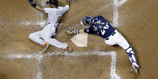 Miami Marlins' Dee Gordon slides safely past Milwaukee Brewers catcher Jonathan Lucroy during the fifth inning of a baseball game Monday, Aug. 17, 2015, in Milwaukee. Gordon scored from third on a sacrifice fly by Martin Prado. (AP Photo/Morry Gash)