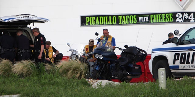 Police detain and watch members of various motorcycle clubs near a Twin Peaks restaurant in Waco, Texas, Sunday, May 17, 2015. A shootout among rival motorcycle gangs at the popular Texas restaurant left nine bikers dead and more than a dozen injured, a police spokesman said Sunday. (AP Photo/John L. Mone)