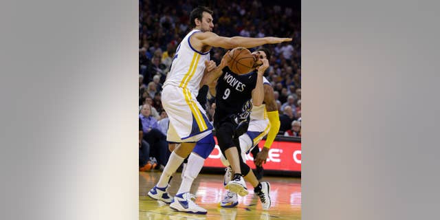 FILE - IN this Jan. 24, 2014, file photo, Golden State Warriors' Andrew Bogut, left, blocks Minnesota Timberwolves' Ricky Rubio during an NBA basketball game in Oakland, Calif. The Warriors will likely be without Bogut when they begin the playoffs this weekend. The loss of Bogut, who has a fractured right rib, leaves the Warriors without their best interior defender. (AP Photo/Ben Margot, File)