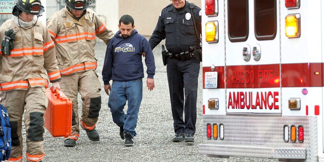In this Jan. 22, 2015 photo, Pasco firefighters and Dean Perry, right, a Pasco police officer, help Antonio Zambrano-Montes, second from right, to an ambulance following a house fire in Pasco, Wash. On Feb. 10, 2015, Zambrano-Montes was fatally shot by police after he ran from them after throwing rocks at cars at an intersection in Pasco. Reports about Zambrano-Montes' interactions with police, obtained by The Associated Press through a public records request, provide new details about his behavior and the extent to which the Pasco Police Dept. was aware of his issues. (Bob Brawdy/Tri-City Herald via AP)