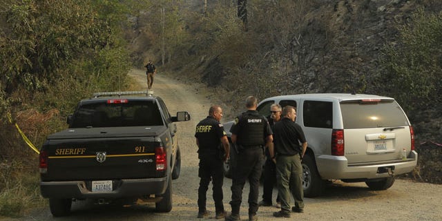 FILE - In this Thursday, Aug. 20, 2015, file photo, Okanogan County Sheriff's deputies guard the entrance to Woods Canyon Road near Twisp, Wash. (AP Photo/Ted S. Warren, File)