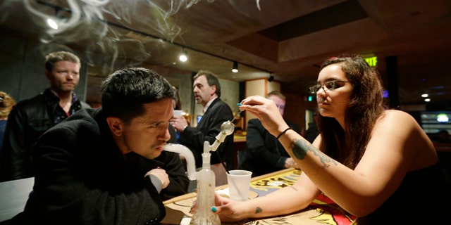 March 2, 2013: John Connelly, left, inhales marijuana vapor with the help of bar worker Jenae DeCampo, right, in the upstairs lounge area of Stonegate, a pizza-and-rum bar in Tacoma, Wash.