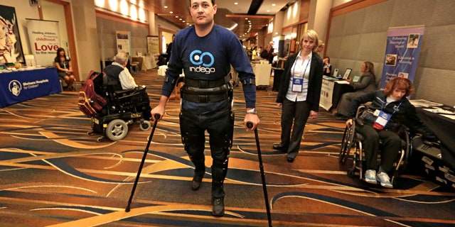 May 6, 2013: Michael Gore, center, who is paralyzed from a spinal injury, walks with the use of the Indego wearable robot under the supervision of physical therapist Clare Hartigan during a meeting of the American Spinal Injury Association at a downtown hotel in Chicago.
