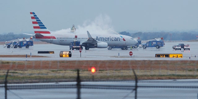 Crews spray deicing solution onto an American Airlines 737 before departure at Dallas-Fort Worth International airport, Monday, Nov. 25, 2013. Winter weather has caused travel disruptions throughout the area including the cancellation and delays of hundreds of flights. (AP Photo/Brandon Wade)