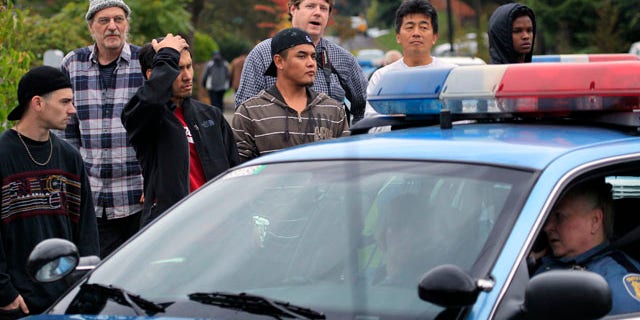 Neighbors look on at the scene of a shooting that left four people dead and another wounded Thursday, Sept. 23, 2010, in Seattle. The woman suspected of firing the shots at the southwest Seattle home apparently is among the dead. (AP Photo/Elaine Thompson)