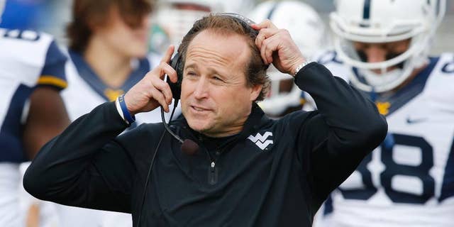 FILE - In this Nov. 16, 2013 file photo, West Virginia head coach Dana Holgorsen adjusts his headset during the first half of an NCAA college football game against Kansas at Kansas Memorial Stadium in Lawrence, Kan. The Mountaineers begin spring practice on Sunday, March 2, 2014, in Morgantown. (AP Photo/Orlin Wagner, File)
